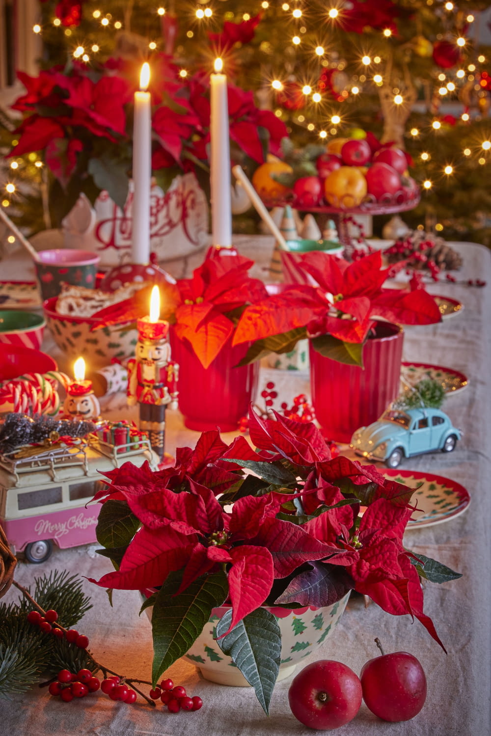 a table topped with red poinsettias and candles
