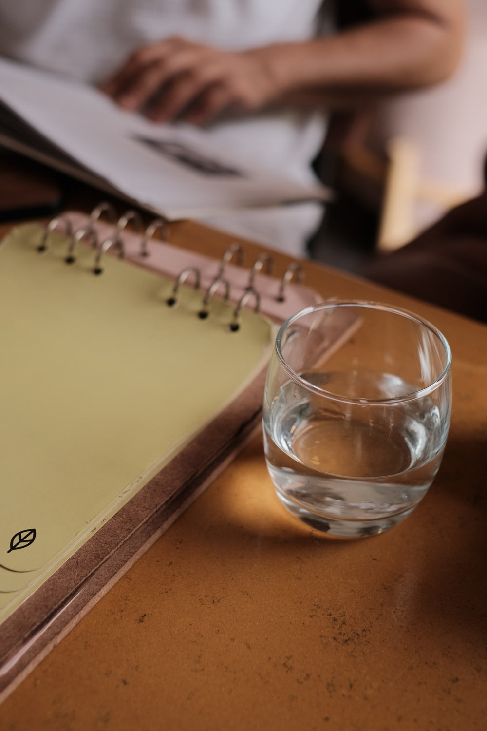 a glass of water sitting next to a notebook
