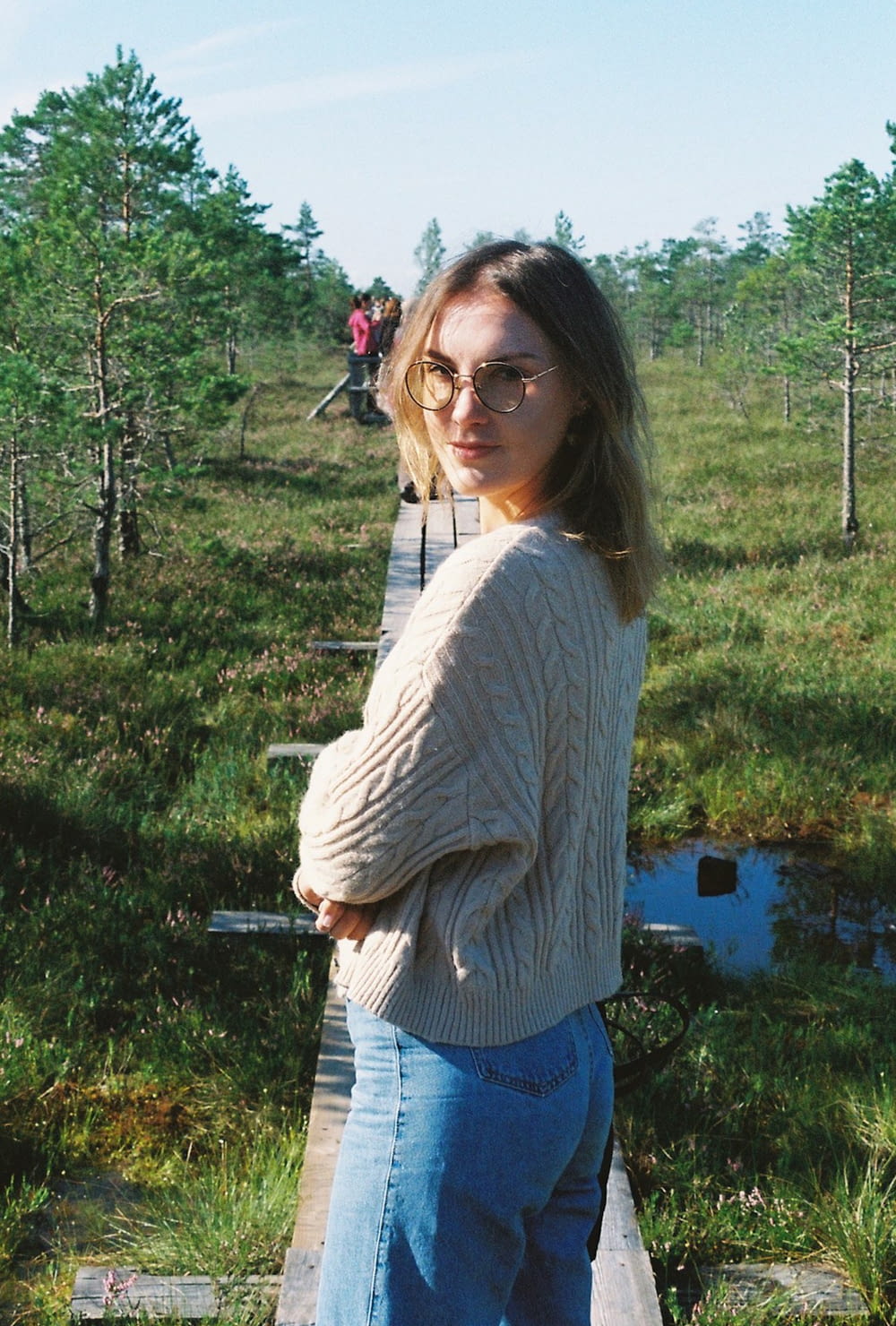 a woman standing on a wooden bridge in a field