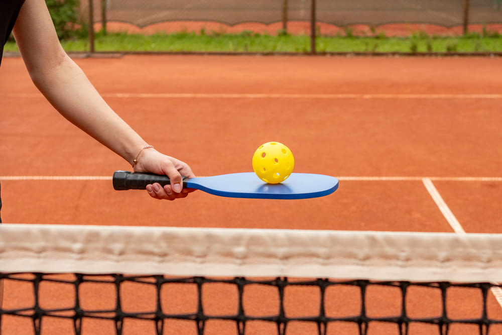 a person holding a tennis racket with a ball on it