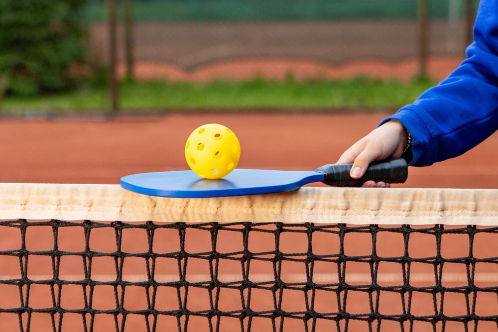 a person holding a tennis racket with a yellow ball on it