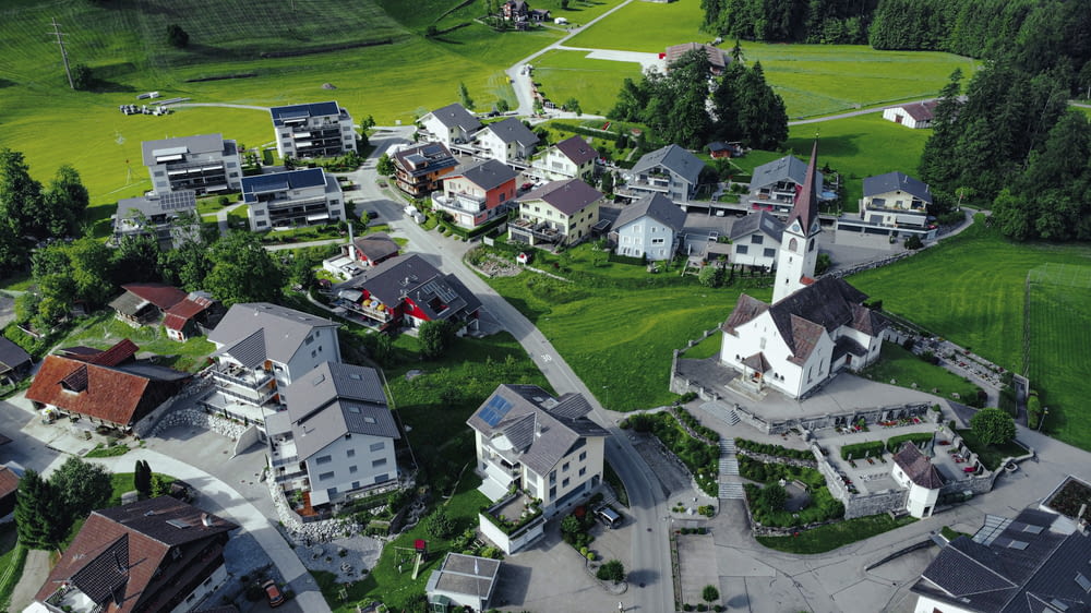 an aerial view of a village with a green field in the background