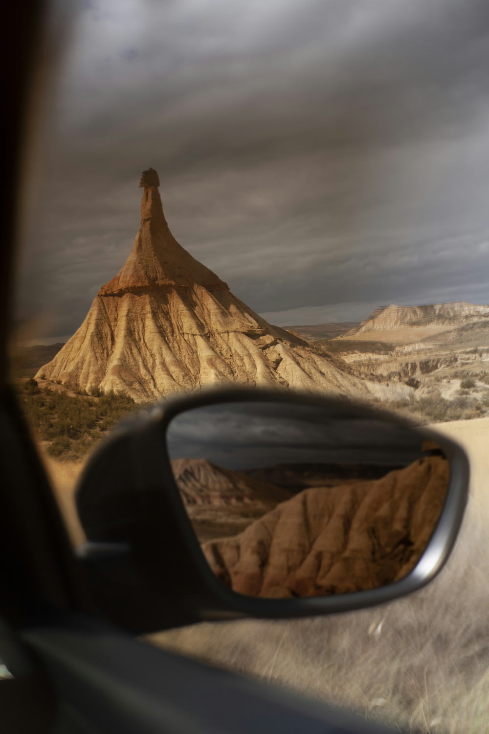 a car's view of a mountain in the rear view mirror