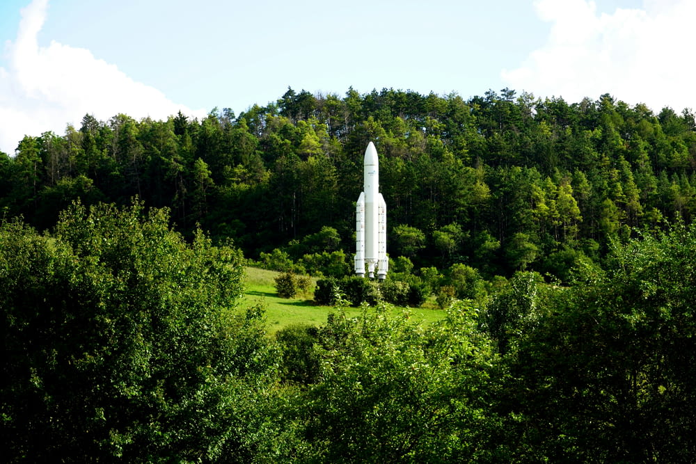 a large white rocket sitting in the middle of a forest