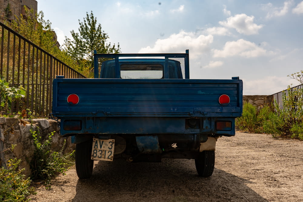 a blue pick up truck parked on a dirt road