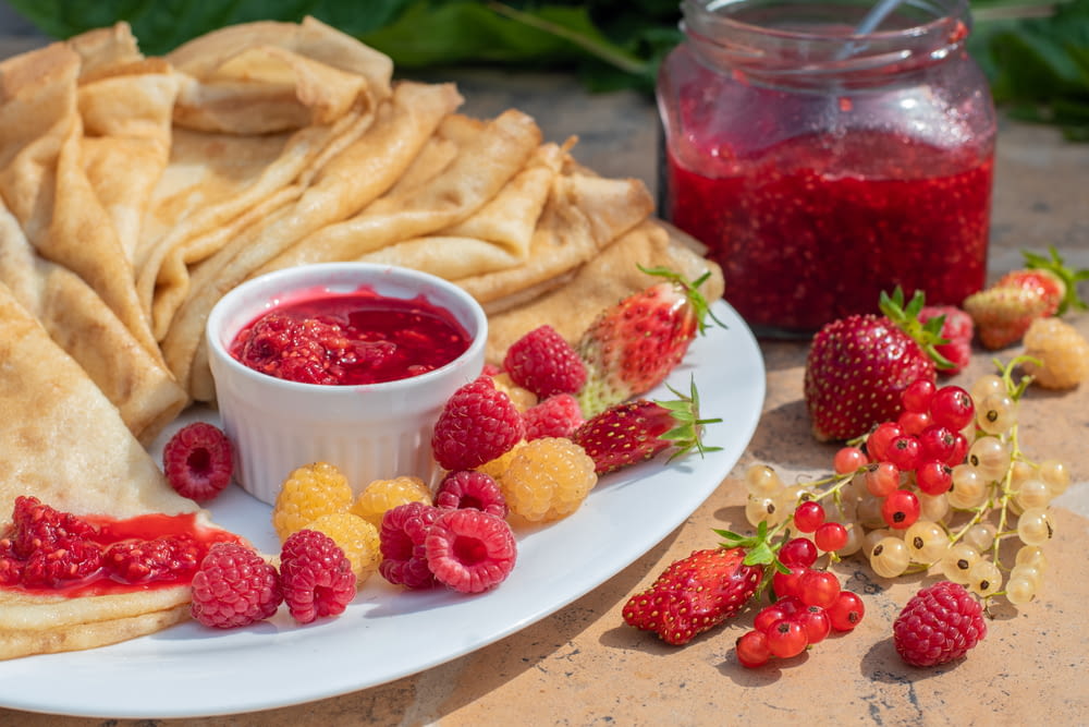 a plate of food with raspberries and a bowl of jelly