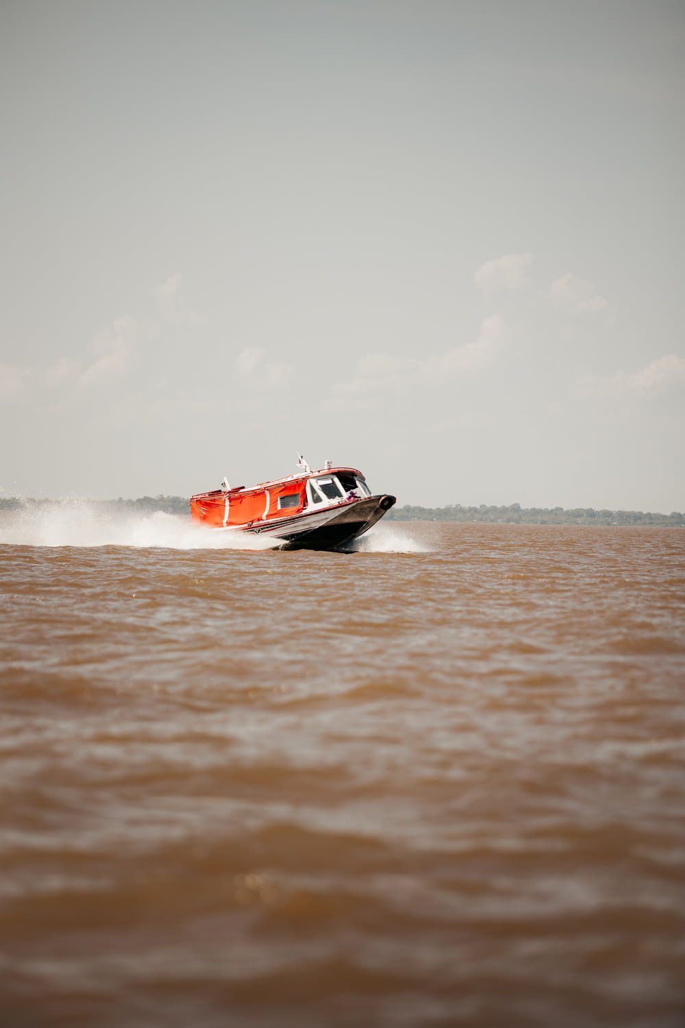 a red and white boat traveling across a body of water