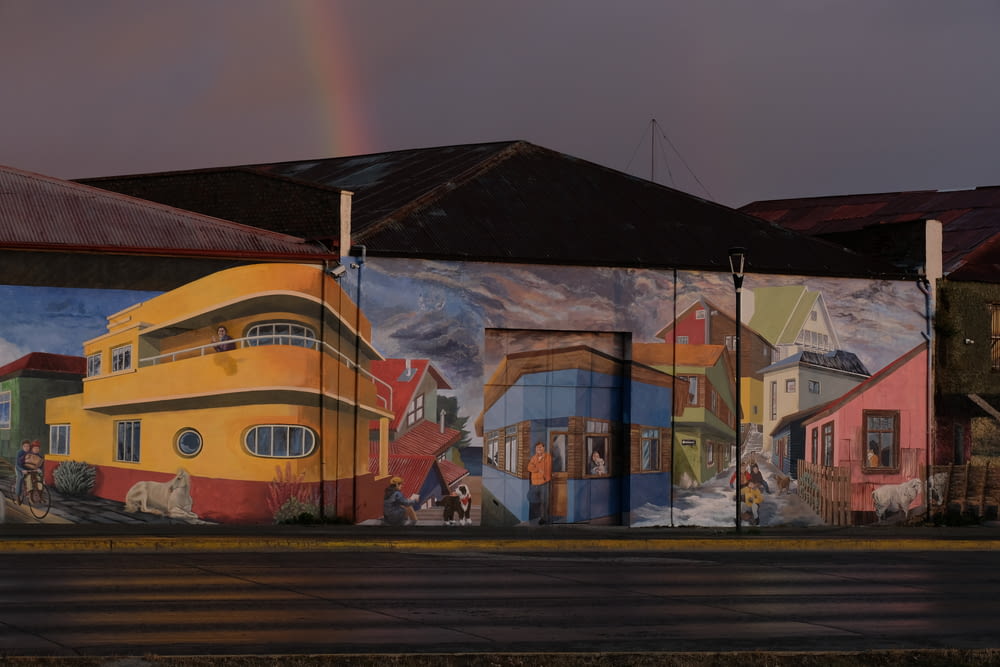 a mural on the side of a building with a rainbow in the background
