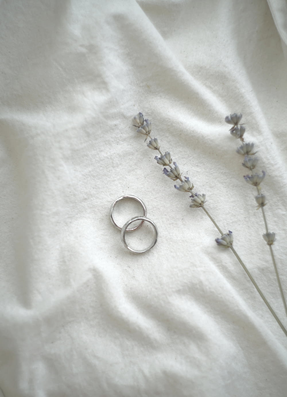 um par de anéis de prata sentados em cima de um lençol branco