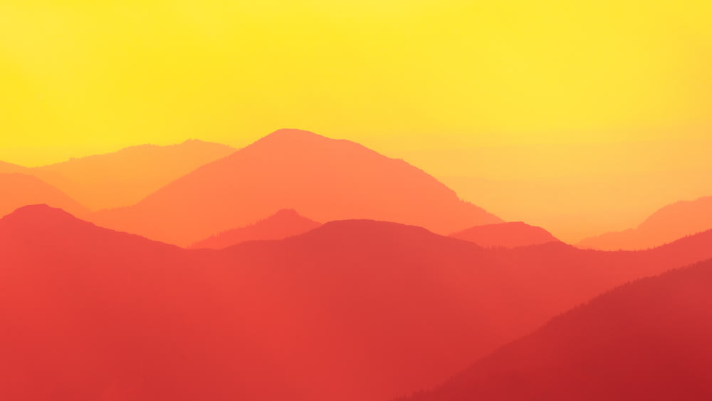 a yellow and red sky with mountains in the background