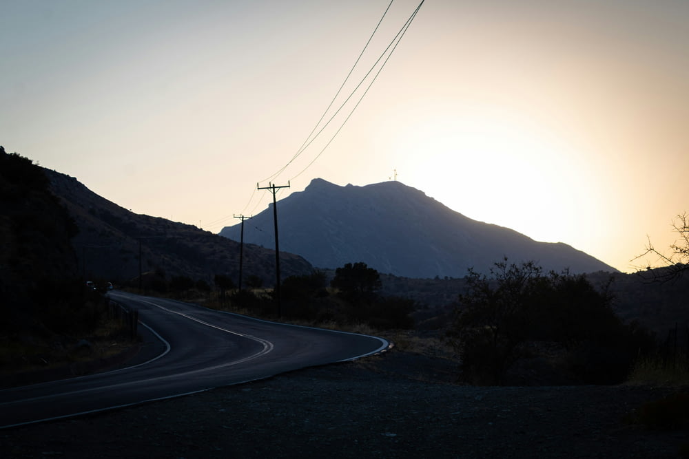 the sun is setting on a mountain road