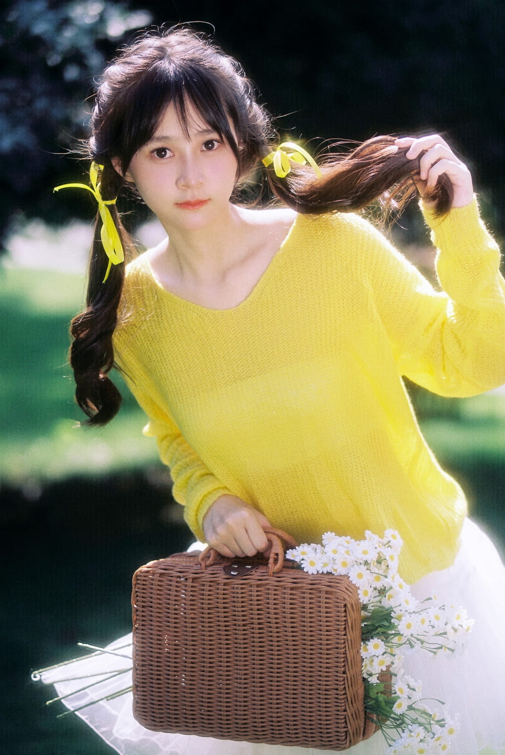 a woman in a yellow sweater holding a suitcase