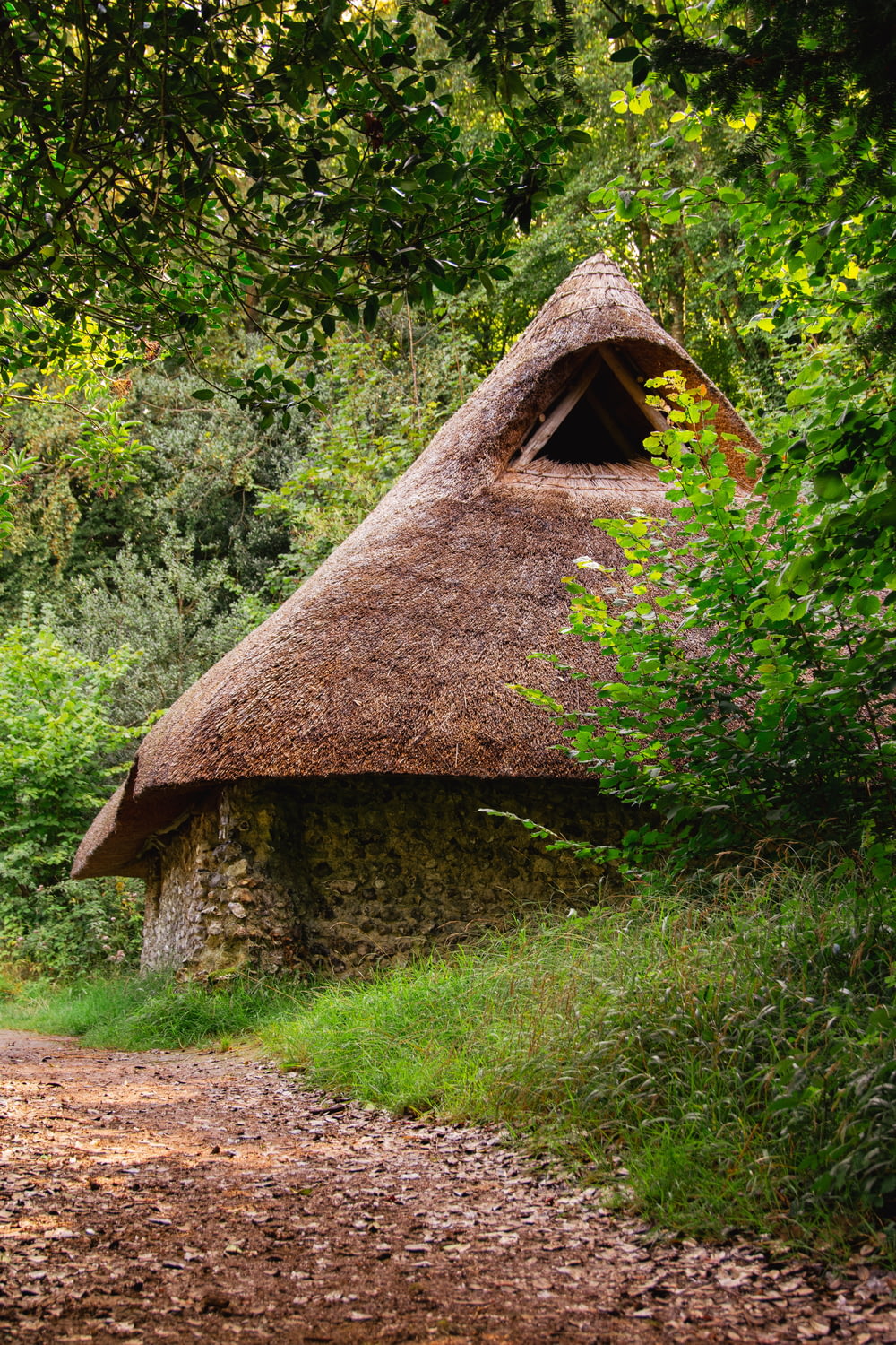 a stone building with a thatched roof in the woods