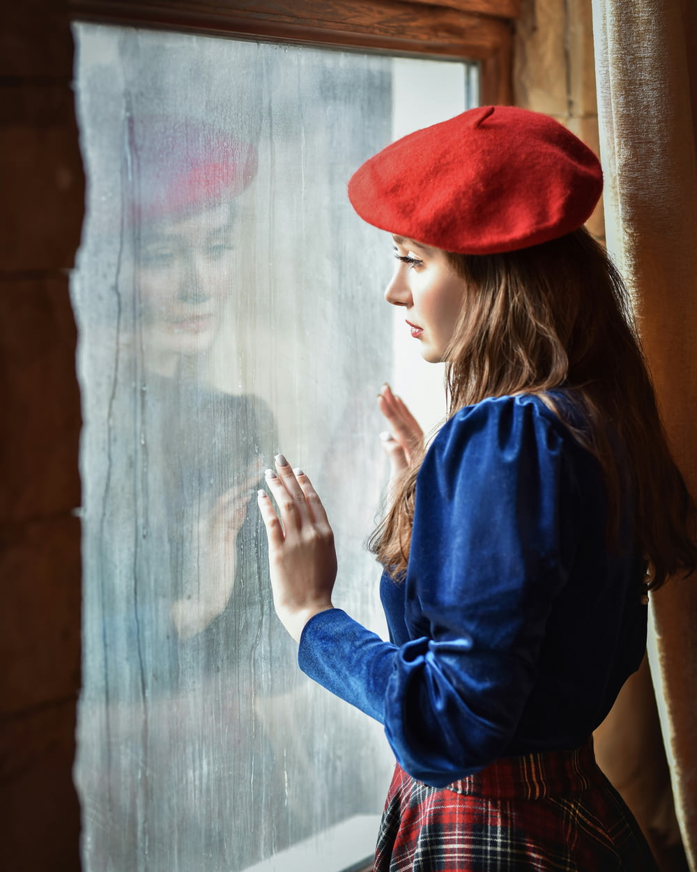 a woman in a red hat looking out a window