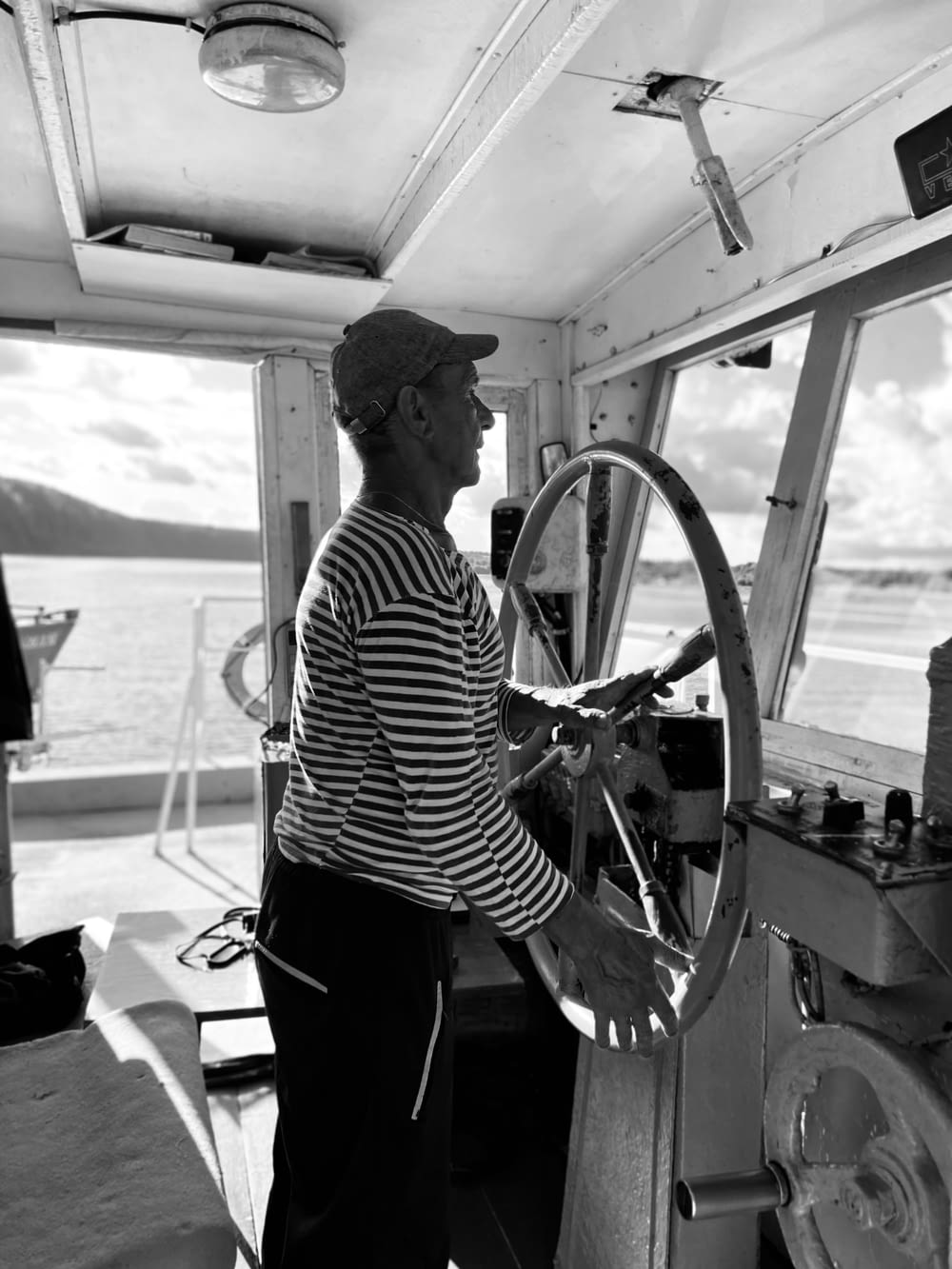 a man standing at the wheel of a boat