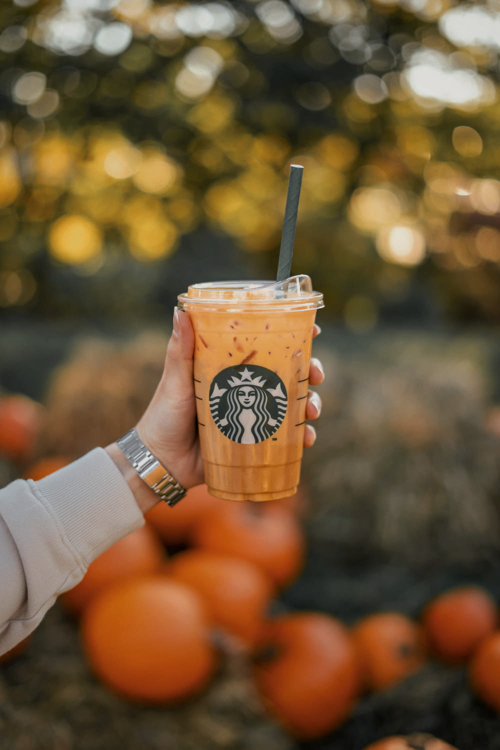 a person holding a starbucks drink with oranges in the background