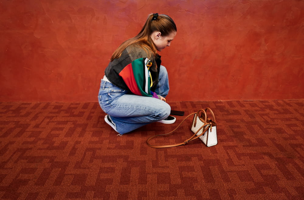 a woman sitting on the floor with a purse