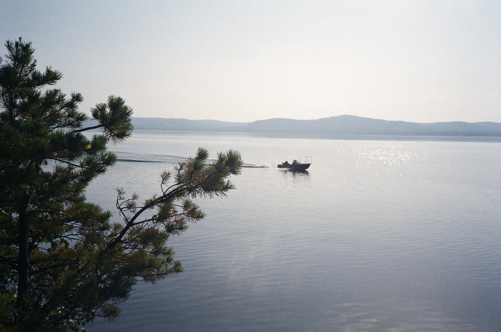 a lone boat on a calm lake with mountains in the background