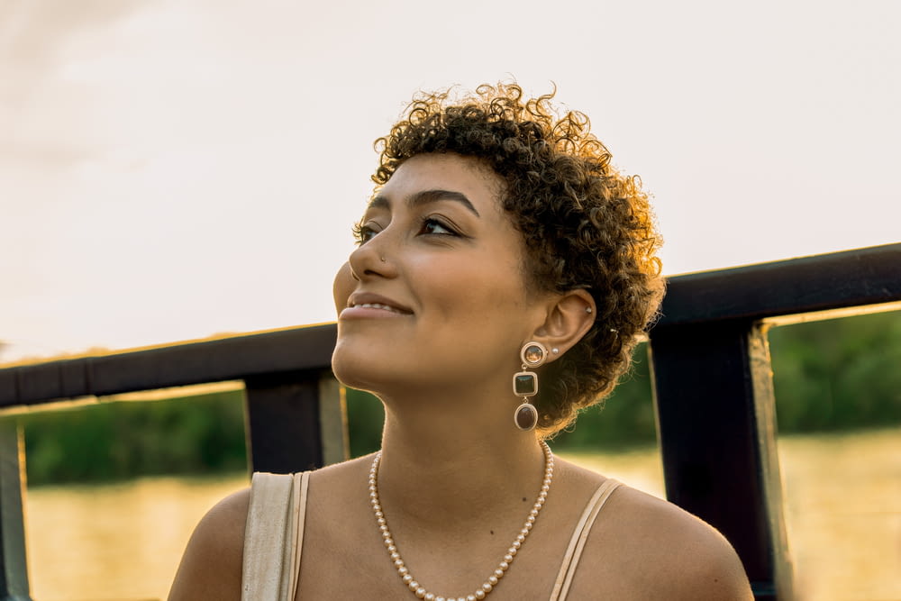 a woman wearing a necklace and earrings looking up