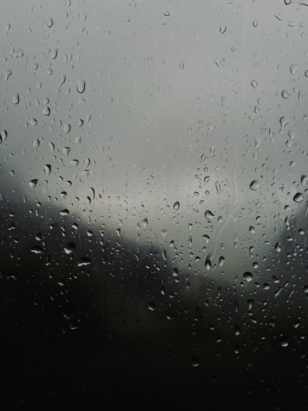 rain drops on a window with a cloudy sky in the background