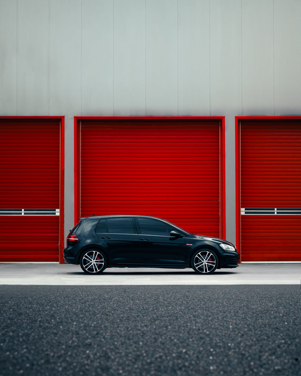 a black car parked in front of a red garage door