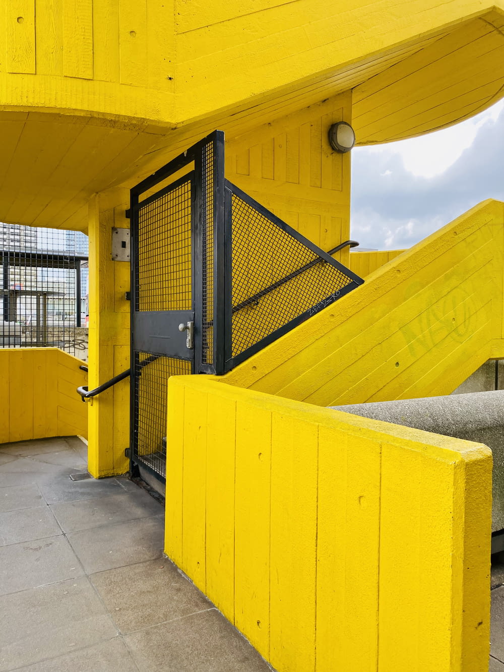 a yellow building with stairs and a bench in front of it