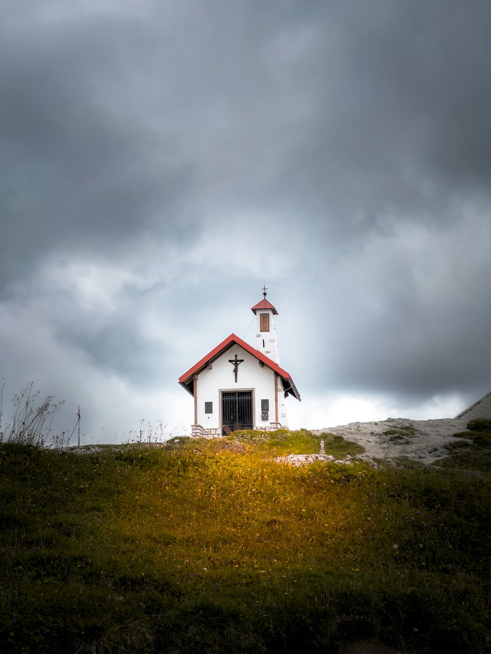 a small church on a hill under a cloudy sky