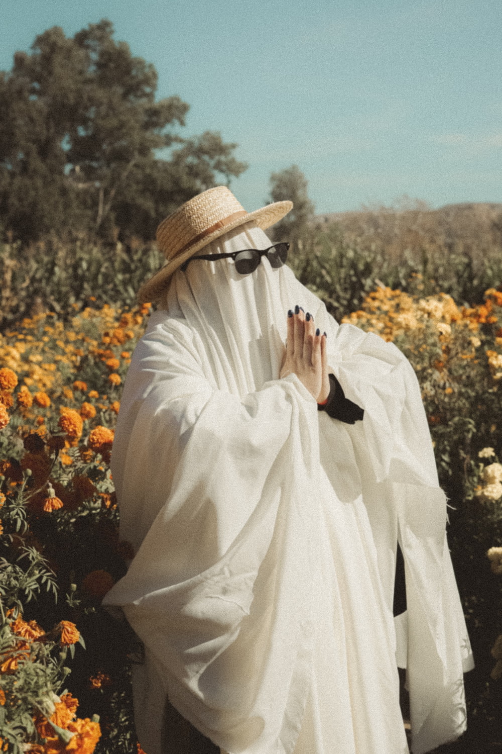a person in a white robe and hat in a field of flowers