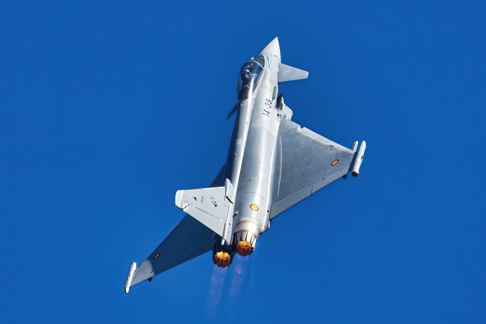 a silver fighter jet flying through a blue sky