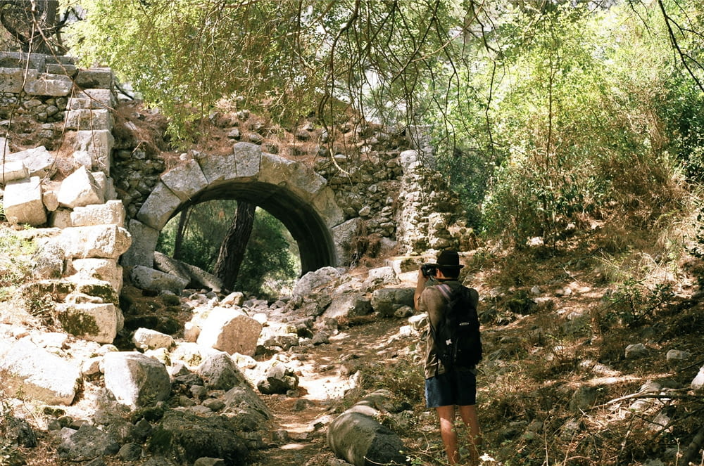 a man standing in front of a stone tunnel