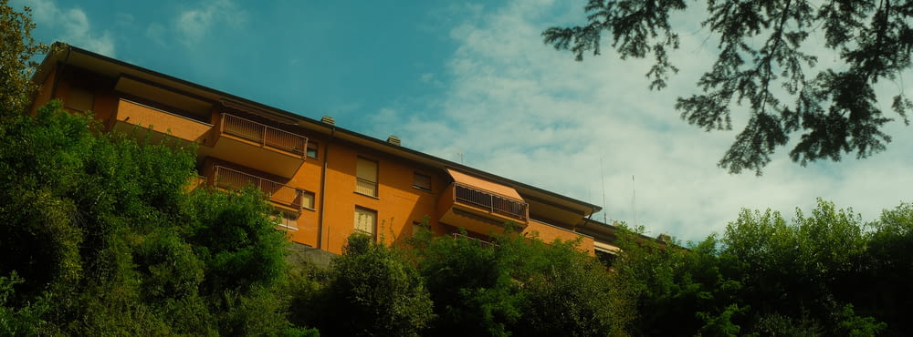 a yellow building on a hill surrounded by trees