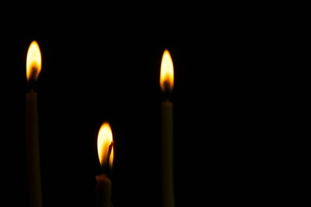 three lit candles in the dark on a table