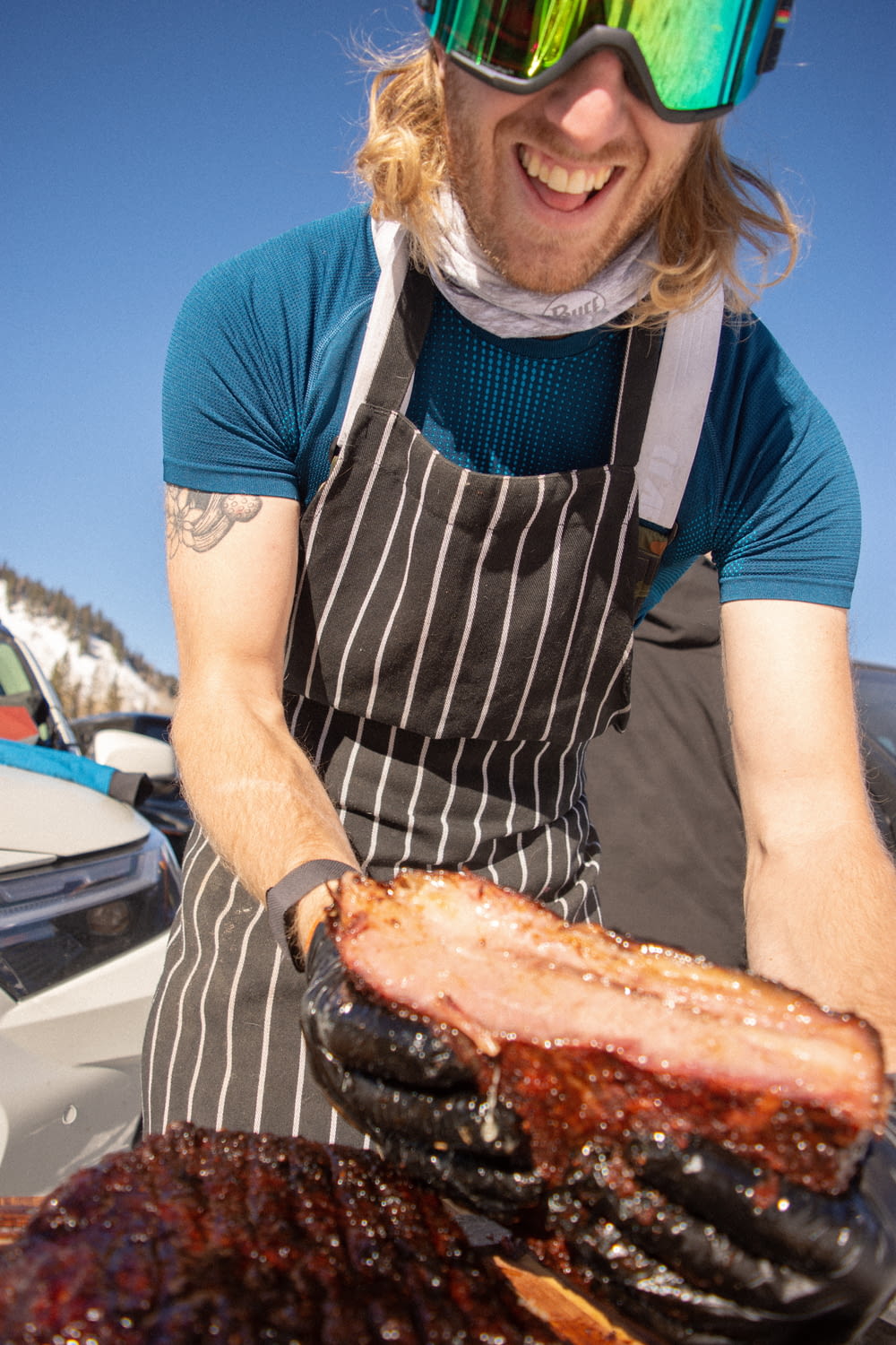 a man wearing a pair of ski goggles holding a large piece of meat