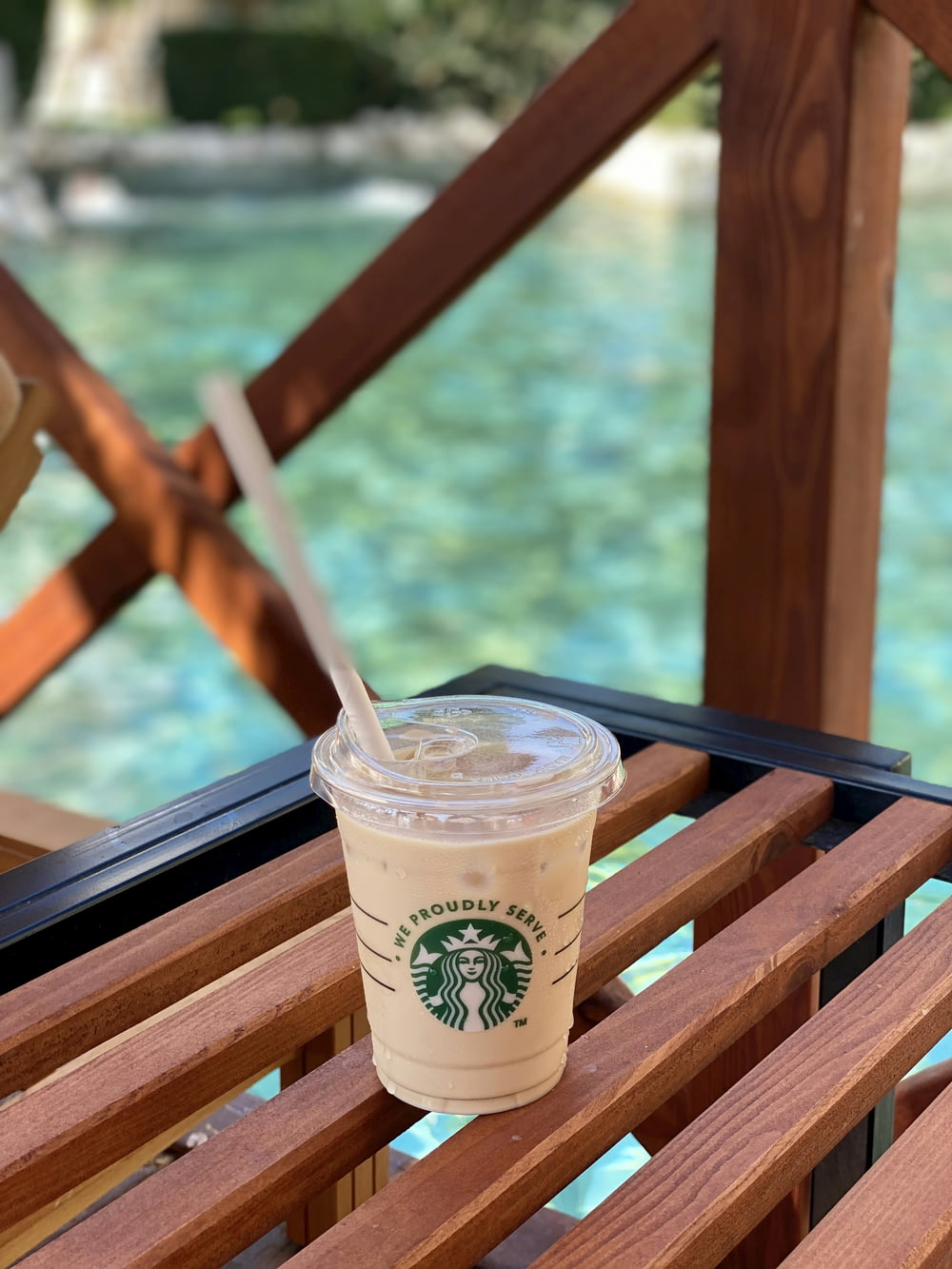 a cup of starbucks coffee sitting on a wooden bench