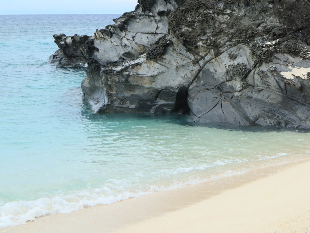 une plage de sable à côté d’une grande formation rocheuse