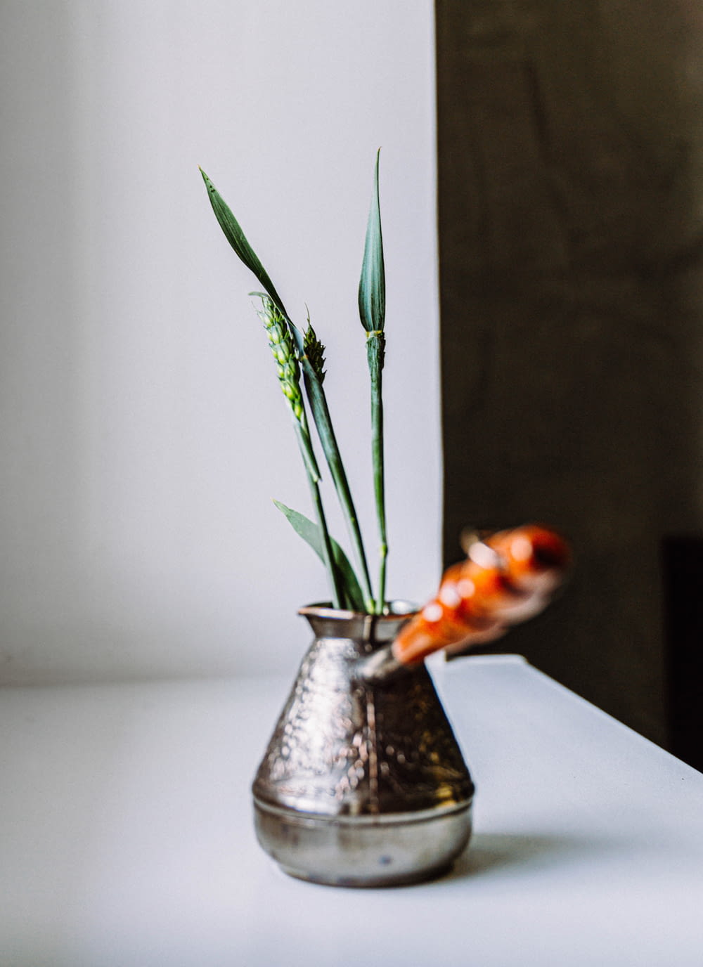 un vaso di metallo con fiori su un tavolo