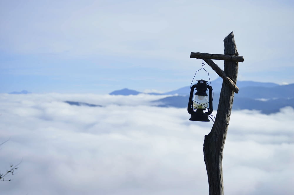 a lantern hanging from a wooden pole above the clouds