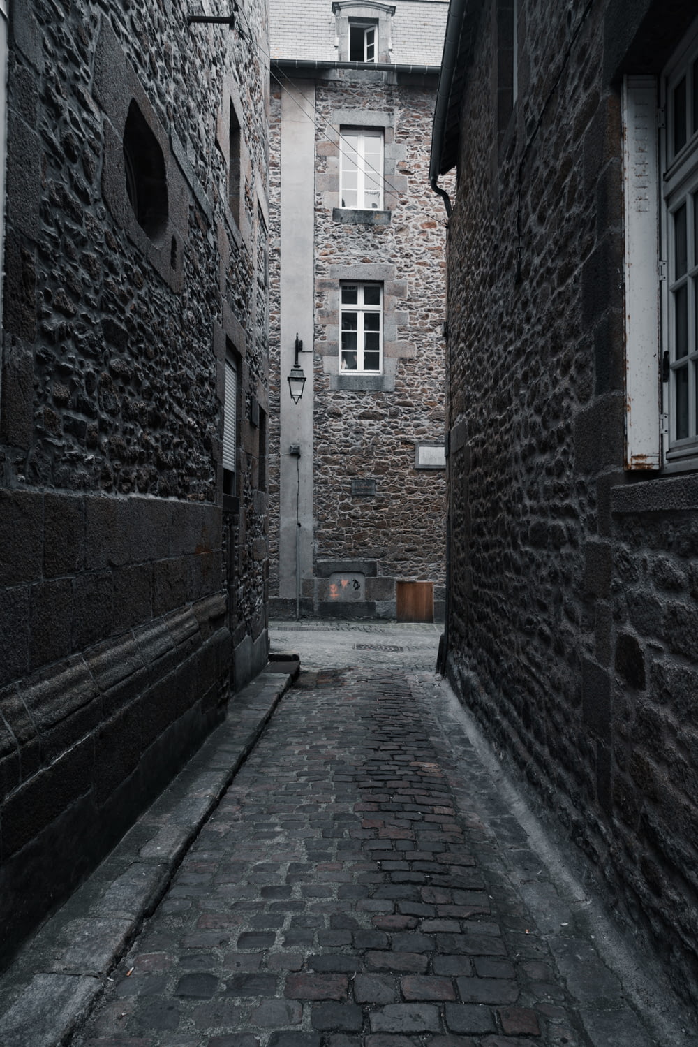 a narrow alley with a stone building in the background