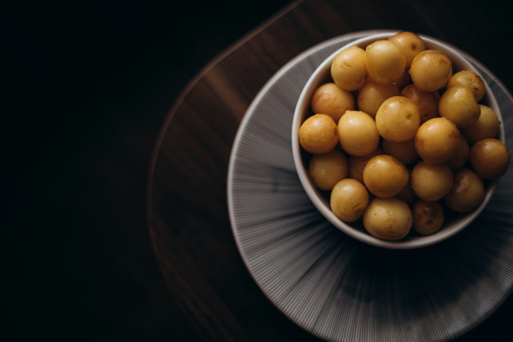 a white bowl filled with yellow potatoes on top of a wooden table