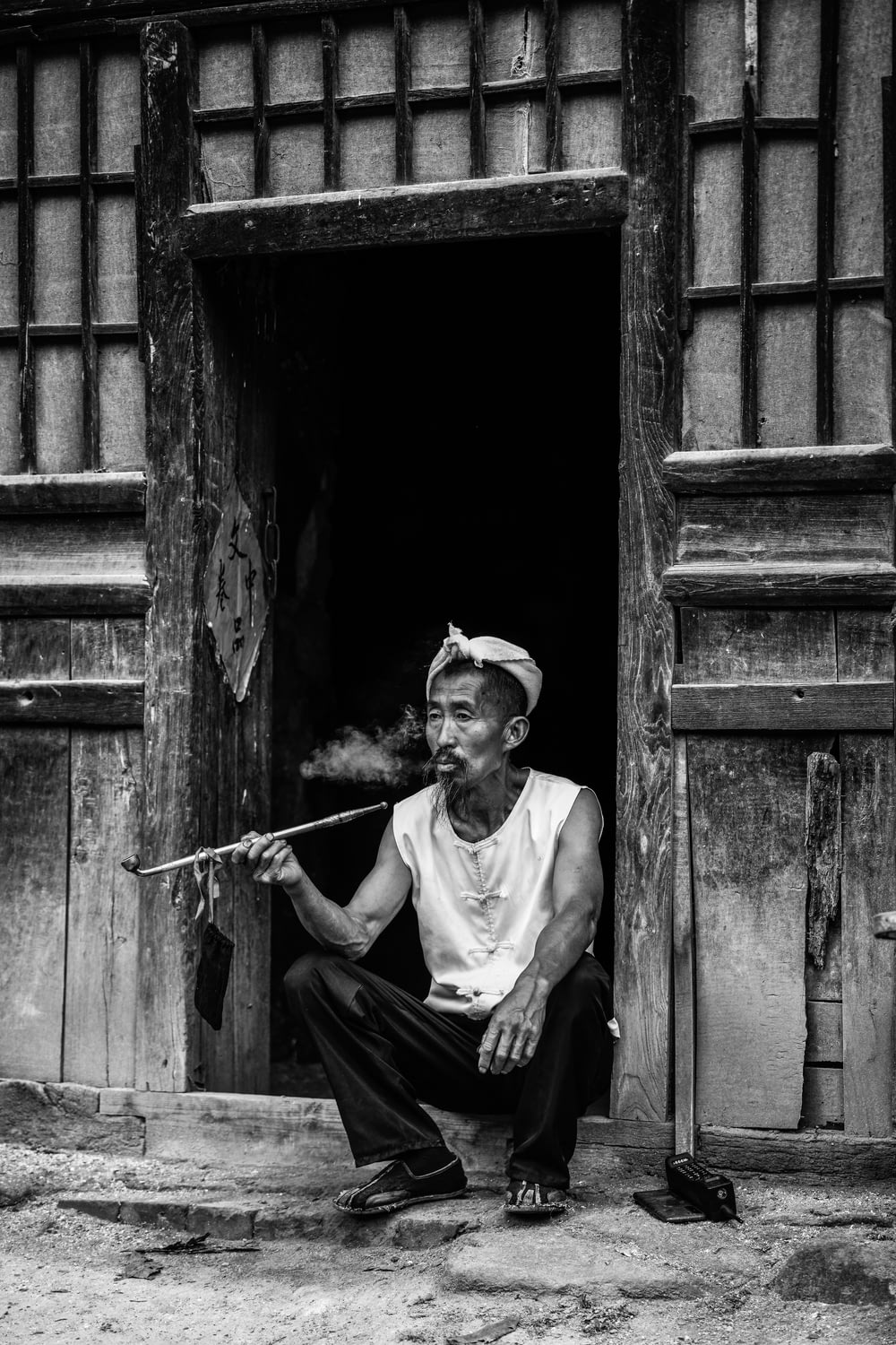 a man sitting in a doorway smoking a pipe