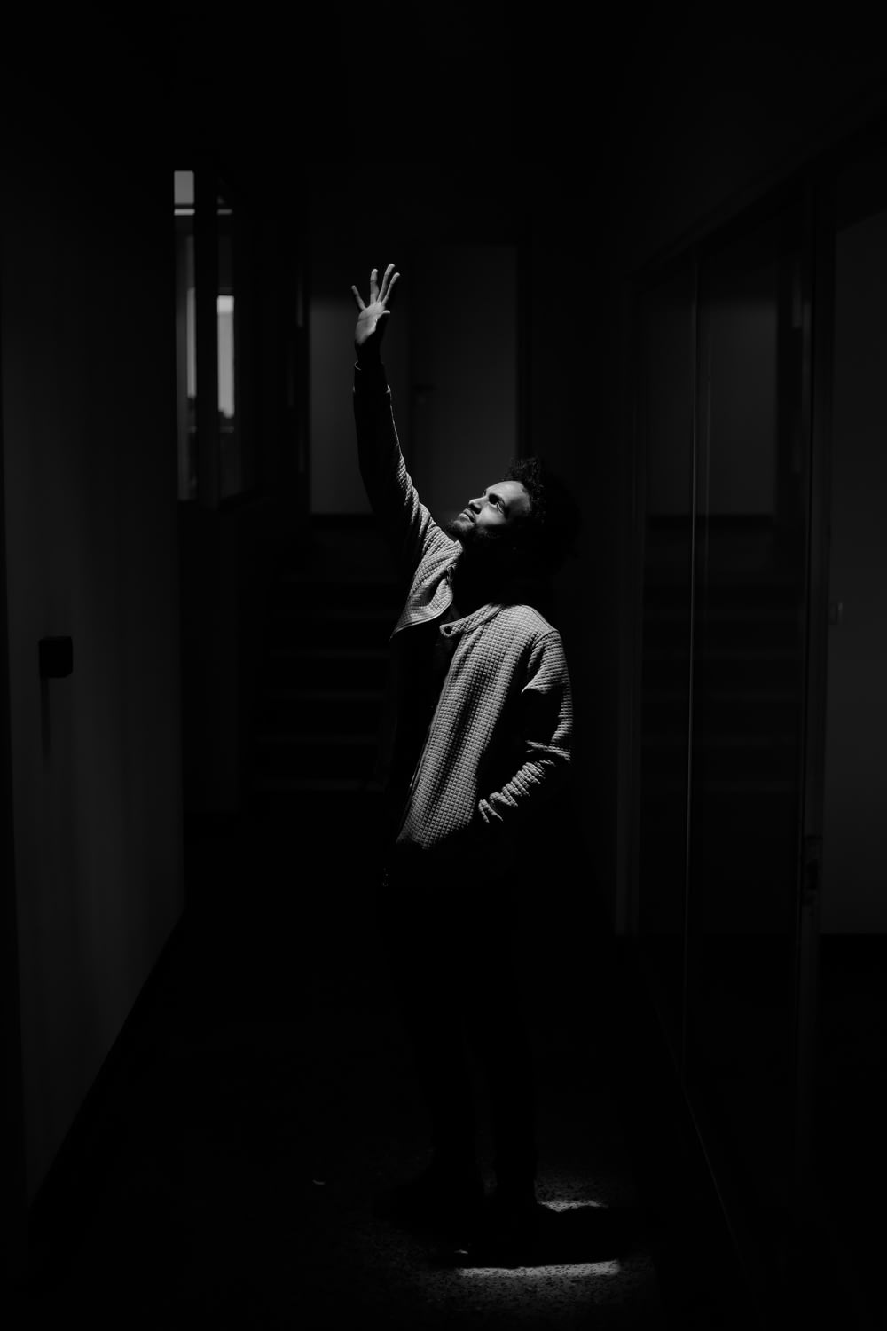 una persona in piedi in una stanza buia che raggiunge l'alto