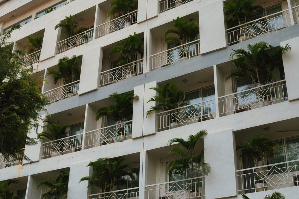 a tall white building with balconies and palm trees