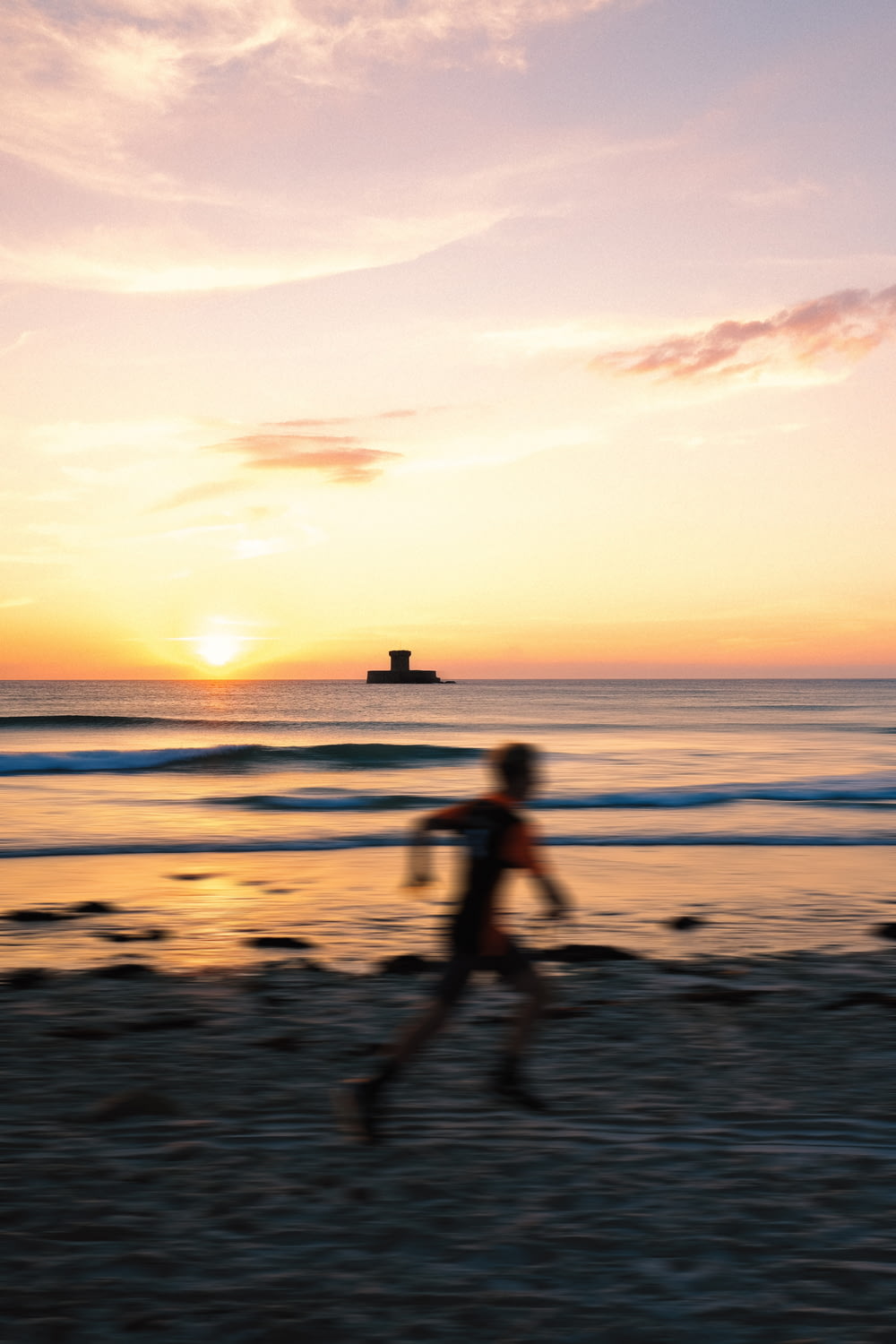 a person running on a beach at sunset