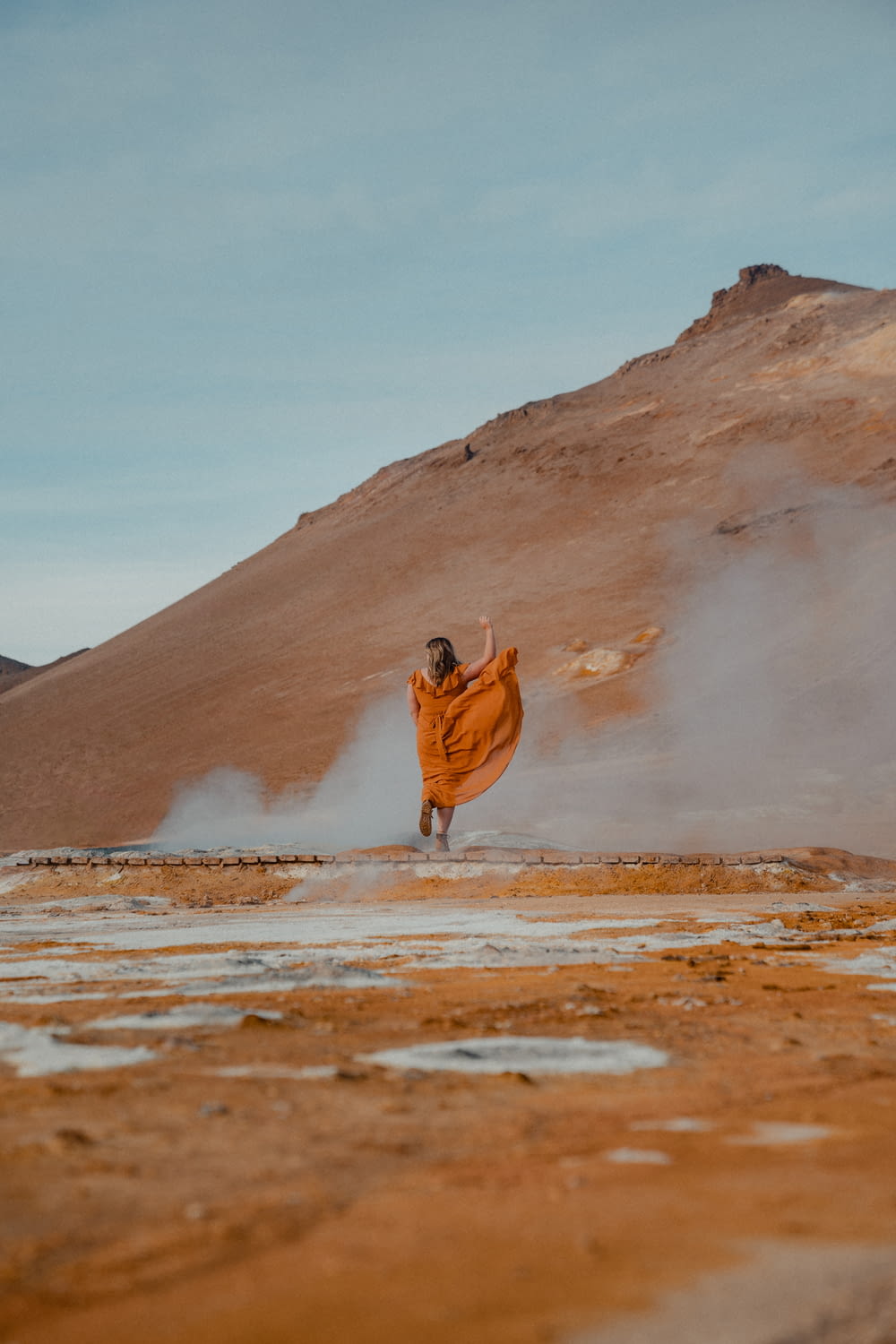 a woman in an orange dress is running in the desert