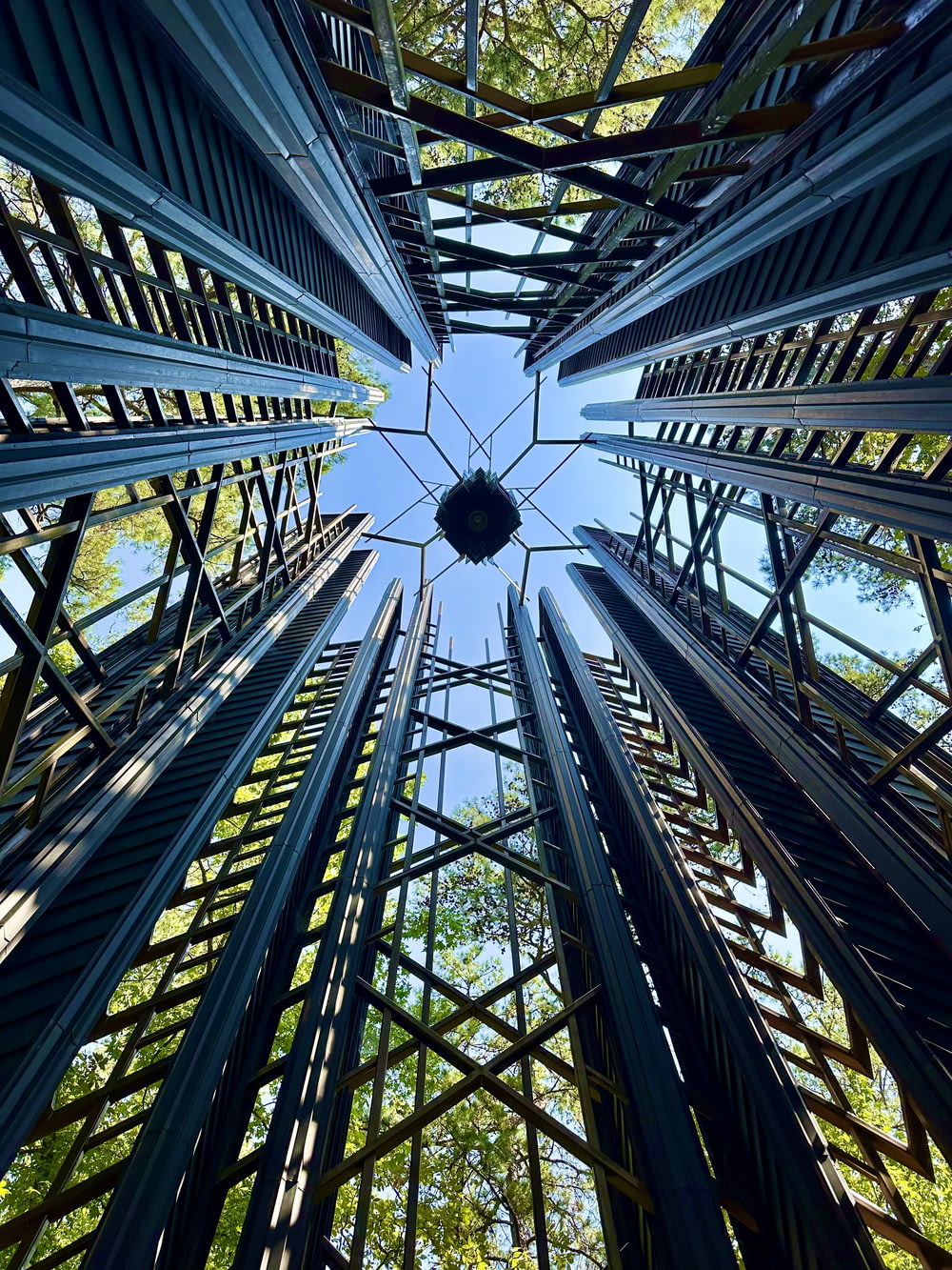olhando para cima para uma estrutura metálica com árvores ao fundo