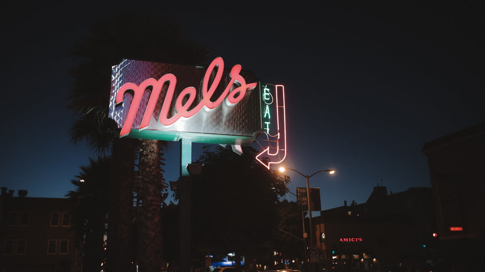 a neon sign that reads mel's on the side of a building