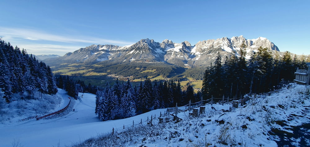 a snow covered mountain with trees and mountains in the background