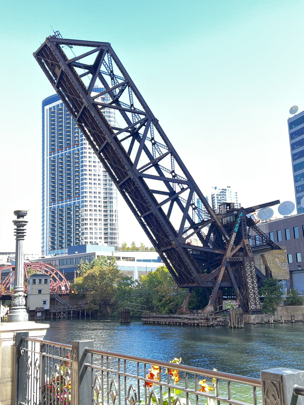 a large metal bridge over a river next to tall buildings