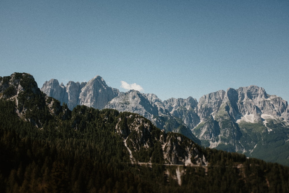 una vista di una catena montuosa con alberi e montagne sullo sfondo