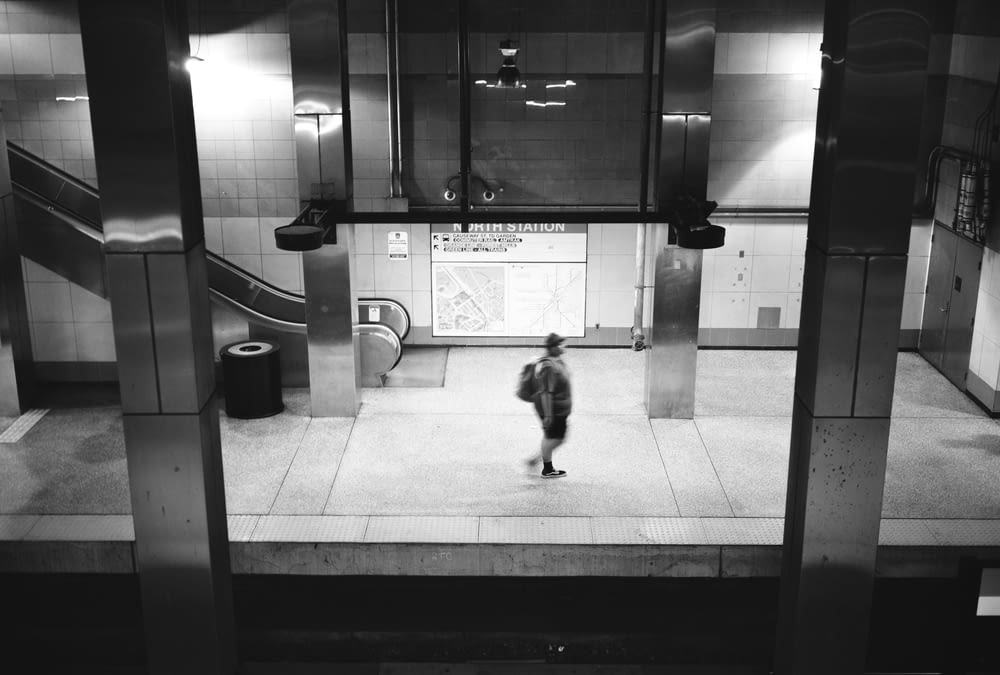 a black and white photo of a person in a subway station